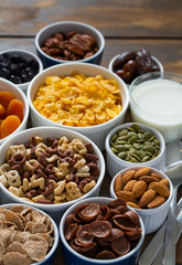 various cereals, nuts and dried fruits on wooden surface