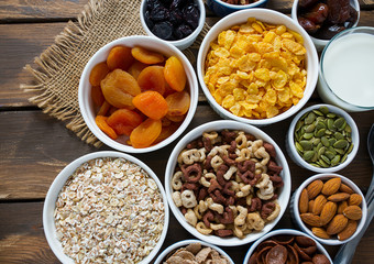 various cereals, nuts and dried fruits on wooden surface