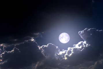 Fototapeta na wymiar The full moon between the clouds in the night sky