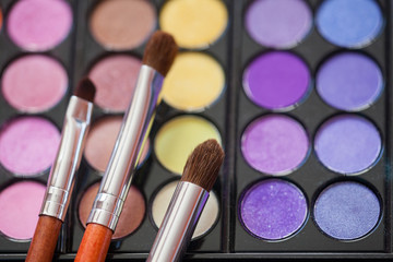 Makeup brushes on background with colorful powder. Macro shooting.