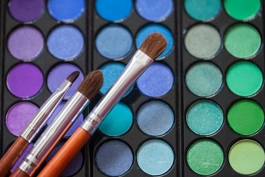 Makeup brushes on background with colorful powder. Macro shooting.
