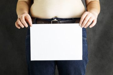 a fat man s belly holds a sheet of white paper clean, or with the inscription steam to lose weight - close-up