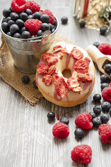 Doughnut with dried strawberries and white chocolate on the wooden rural table.