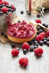 Baked donuts with dried raspberry and a chocolate on the wooden table. The doughnut with many fresh blueberries and raspberry. Rural bakery concept.