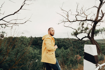a man in a yellow raincoat, sitting on the roadside and photographing