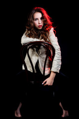 Fototapeta na wymiar elegant woman on black background with red light. Studio shot. High fashion look.glamour portrait of beautiful sexy young female woman with red lips. Sit on chair.