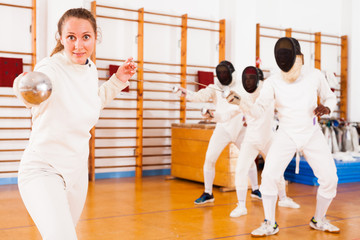 Young female fencer practicing fencing technique in training room
