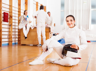 Woman in uniform sitting on floor at fencing training