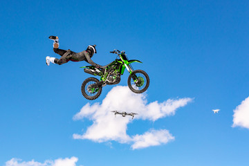 racer on a motorcycle in flight, jumps and takes off on a springboard against the blue sky