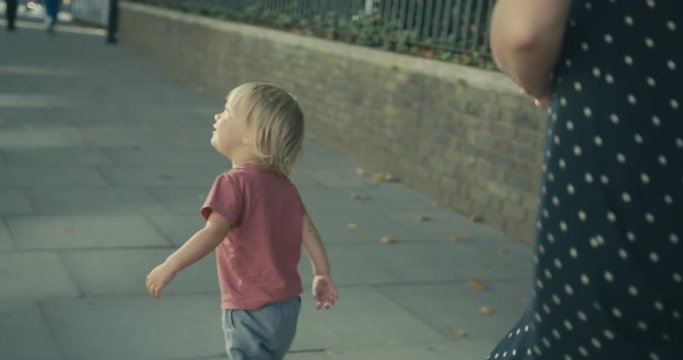 Toddler and woman walking in the street in autumn