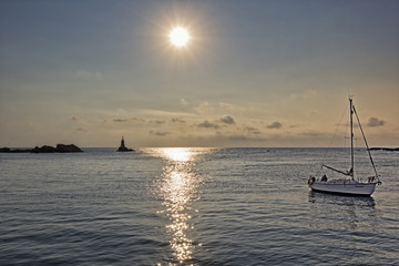 A sailboat floating in the sea at sunrise.