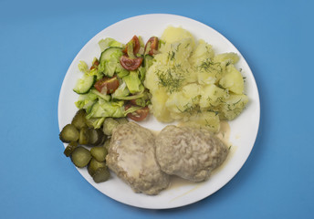 Homemade chicken cutlets with potatoes and various vegetables on blue background