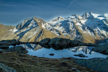 Great view of small lake in Gran Paradiso National Park,  Alps, Italy,  beautiful world. calm scenery with mountains covered by snow in background, majestic mountain landscape, wallpaper