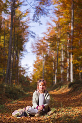 Cute pink haired girl sitting on autumn forest road