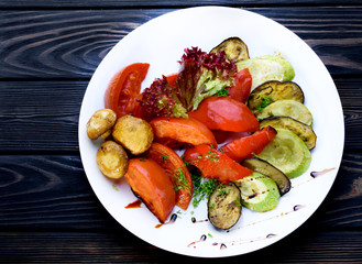 Grilled vegetables in a white plate and with sauce. Tomatoes, mushrooms, zucchini, pepper, eggplant.
