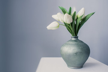 White tulips in a jug on the table - save space - a gift of fresh flowers