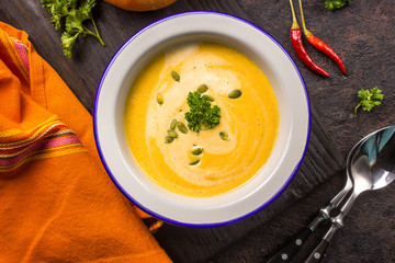 Seasonal autumn food - Spicy pumpkin soup with cream and pumpkin seeds.