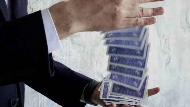 Close-up of magician's hands performing card trick. Throwing and catching cards in the air. Slow motion. HD
