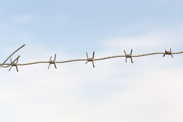 barbed wires against blue sky.
