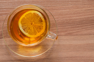 top view of transparent cup with black tea and slice of emon on wooden table