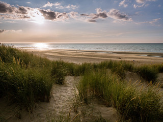 Fototapeta na wymiar Sand path within marram grass covered dunes leads towads the beach just prior sunset in northern France