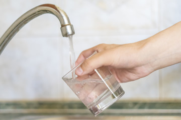 close up hand holding glass fill with water pour from tap d