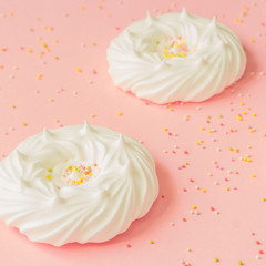 homemade white air meringues and confectionery decorations on pink background