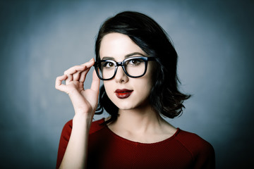 Portrait of a young beautiful lady in glasses over a grey background