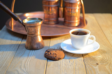 a biscuits and a Cup of coffee near the sugar bowl and container with coffee on rustic wooden table