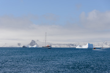 Sailing yacht and iceberg in antarctic sea