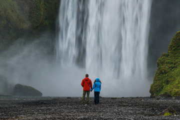 Fototapeta premium Couple looking at powerfull waterfall Skogafoss