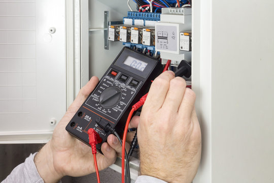 electrician at work measures the electric current