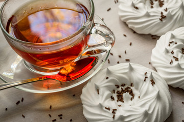 black tea in transparent cup an air homemade meringues close up