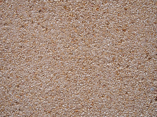 smooth crushed granite pebble textured wall or floor surface background in shades of yellow brown and white