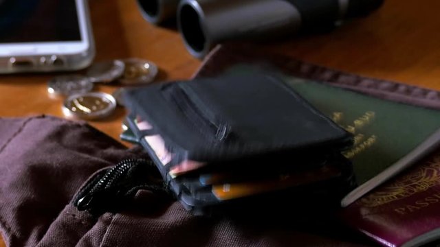 Dropping passports and a wallet onto a desk prior to packing for travel close up.