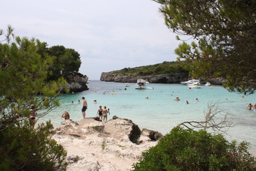 Playa paradisíaca con gente bañándose y el agua del mar de color turquesa