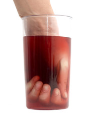 Hand inside a glass in a glass of red compote