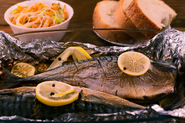 Mackerel baked in a glass container with lemon in foil.