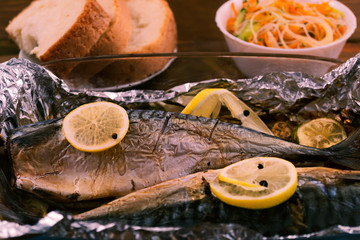 Mackerel baked in a glass container with lemon in foil.