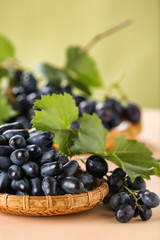 Wicker plate with ripe sweet grapes on table