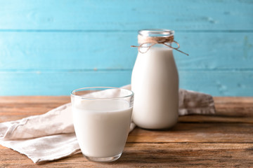 Glass and bottle of milk on wooden background