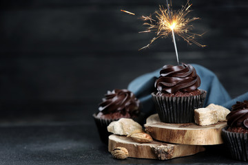 Delicious cupcakes with sparkler on dark table