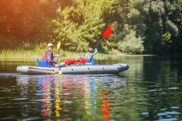 Happy kids kayaking on the river on a sunny day during summer vacation