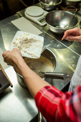 pouring flour into the pan in the preparation of the cream