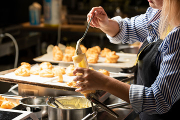 ready-made butter cream for cakes in a spoon that fills the pastry gun in female hands