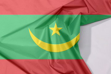 Mauritania fabric flag crepe and crease with white space, Two red stripes flanking a green field with a golden crescent and star.
