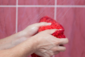 A person bathes in the shower with a washcloth