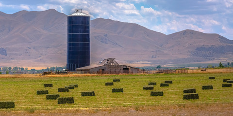 Barn and silo on a farm with haystack on the field © Jason