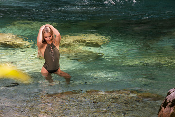 Georgeous young woman standing in her swimsuit in the cold emerald colorful  river