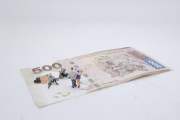a mini beggar begs on bank note